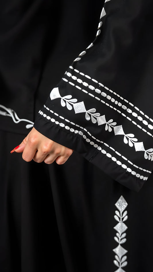 Black garment with white embroidery on a dark background