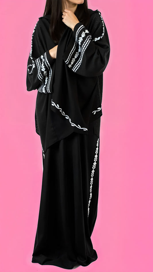 Black outfit with white embroidery on a pink background