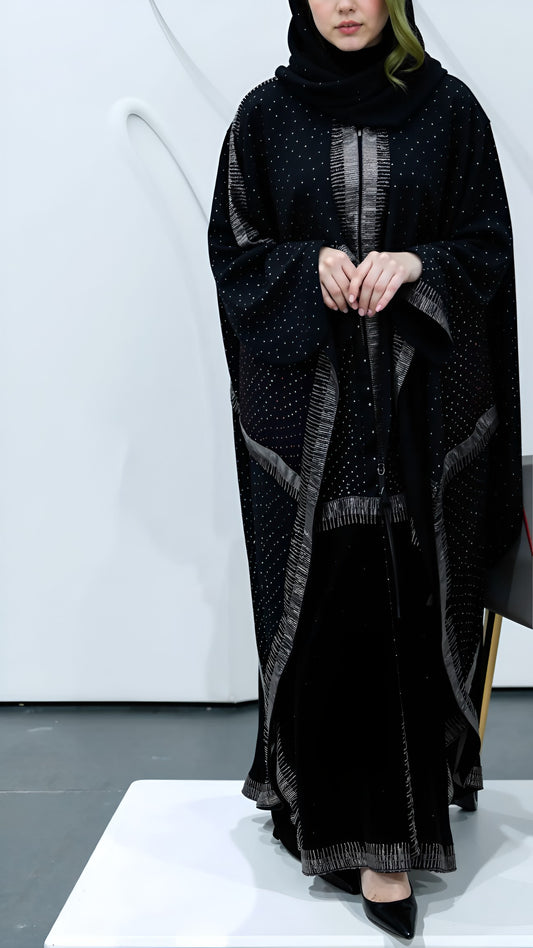 Women wearing a black abaya with intricate patterns on a white background