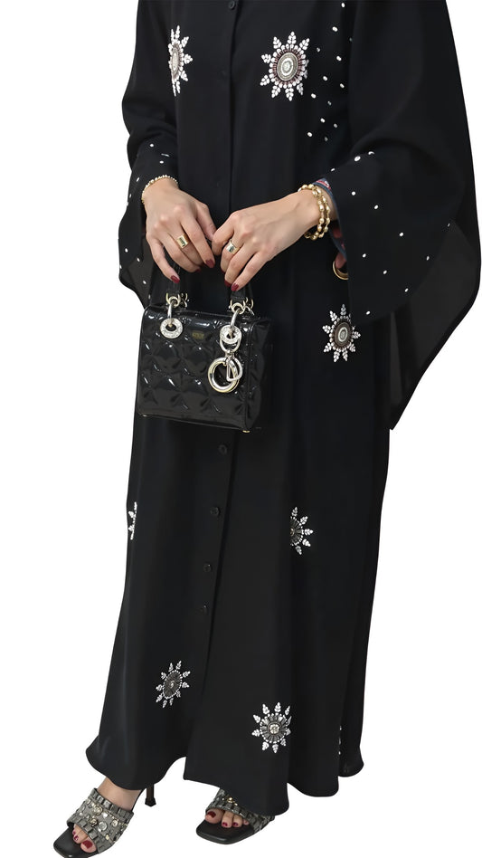 Black outfit with white floral embroidery held by a women against a white background