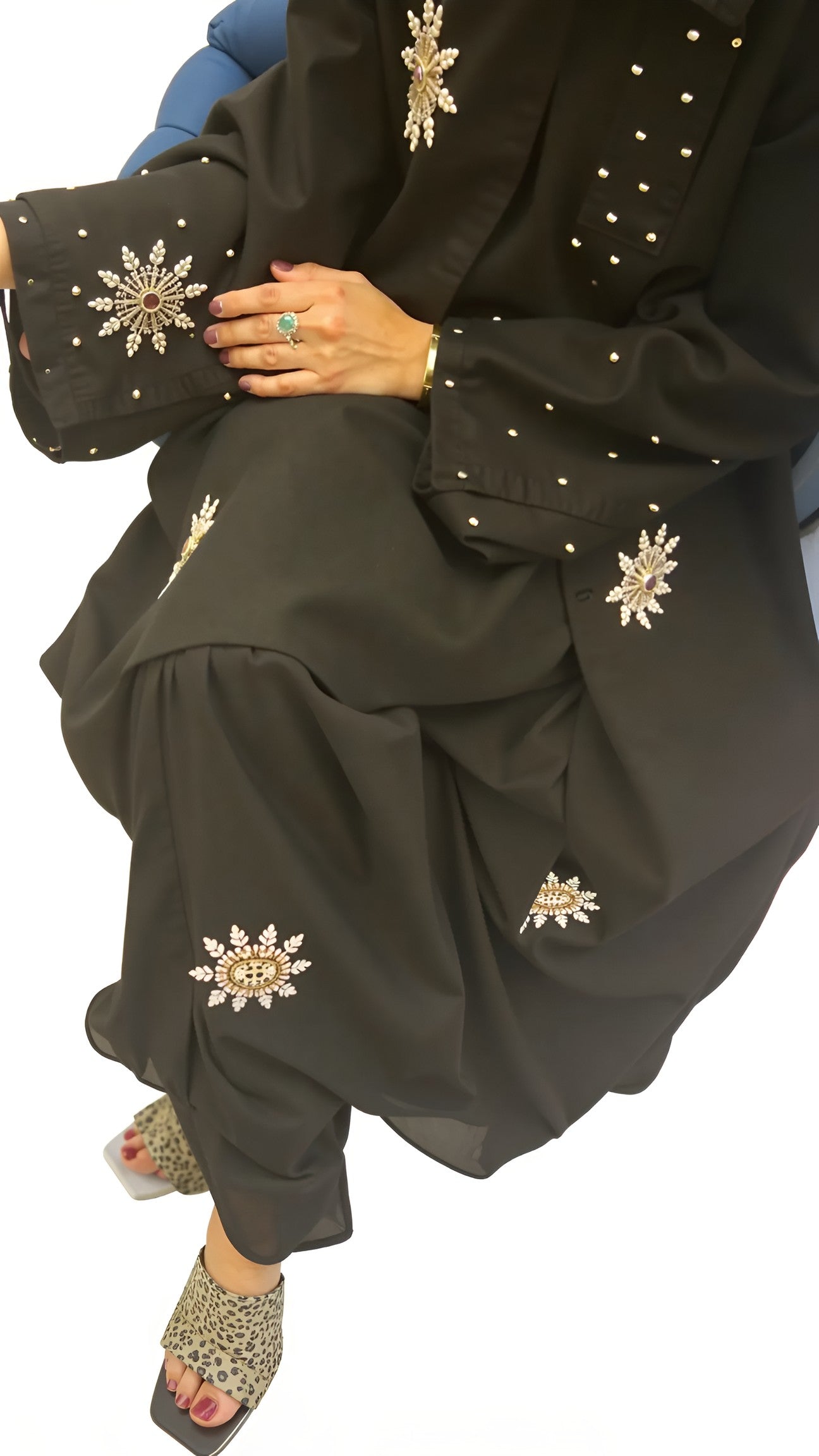 Women wearing a black outfit with gold embroidery, holding a matching clutch.
