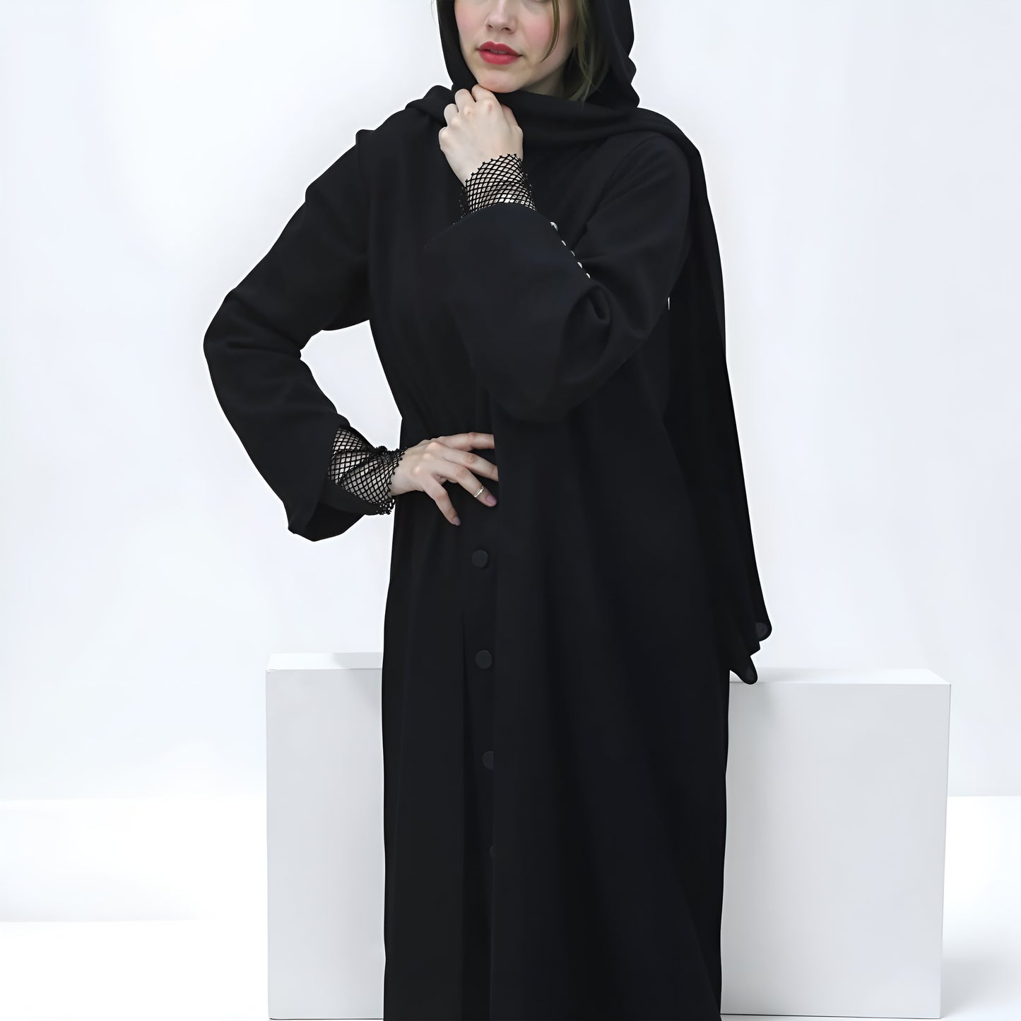 Person wearing a long black dress with sheer sleeves against a white background
