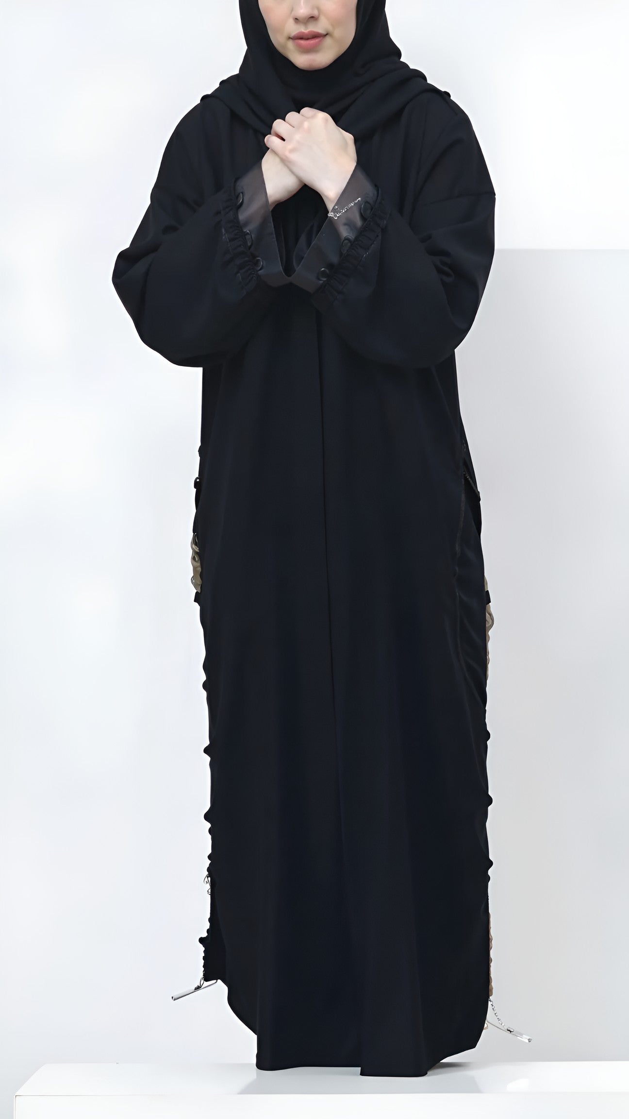 Person wearing a black abaya with floral details on a white background