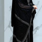 Woman wearing a black abaya with intricate patterns on a marble background
