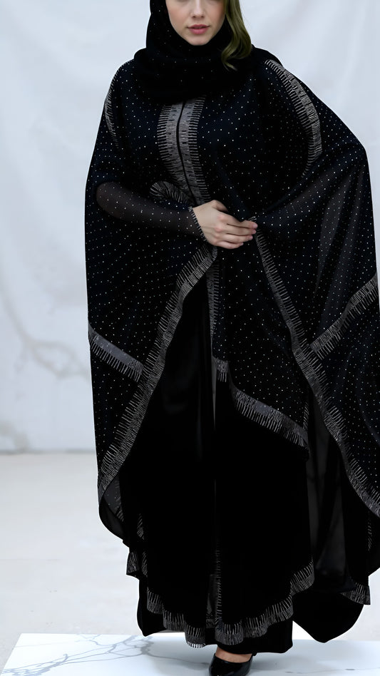 Person wearing a black poncho with a pattern on a white background