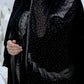 Women wearing a black abaya with intricate designs and embellishments.