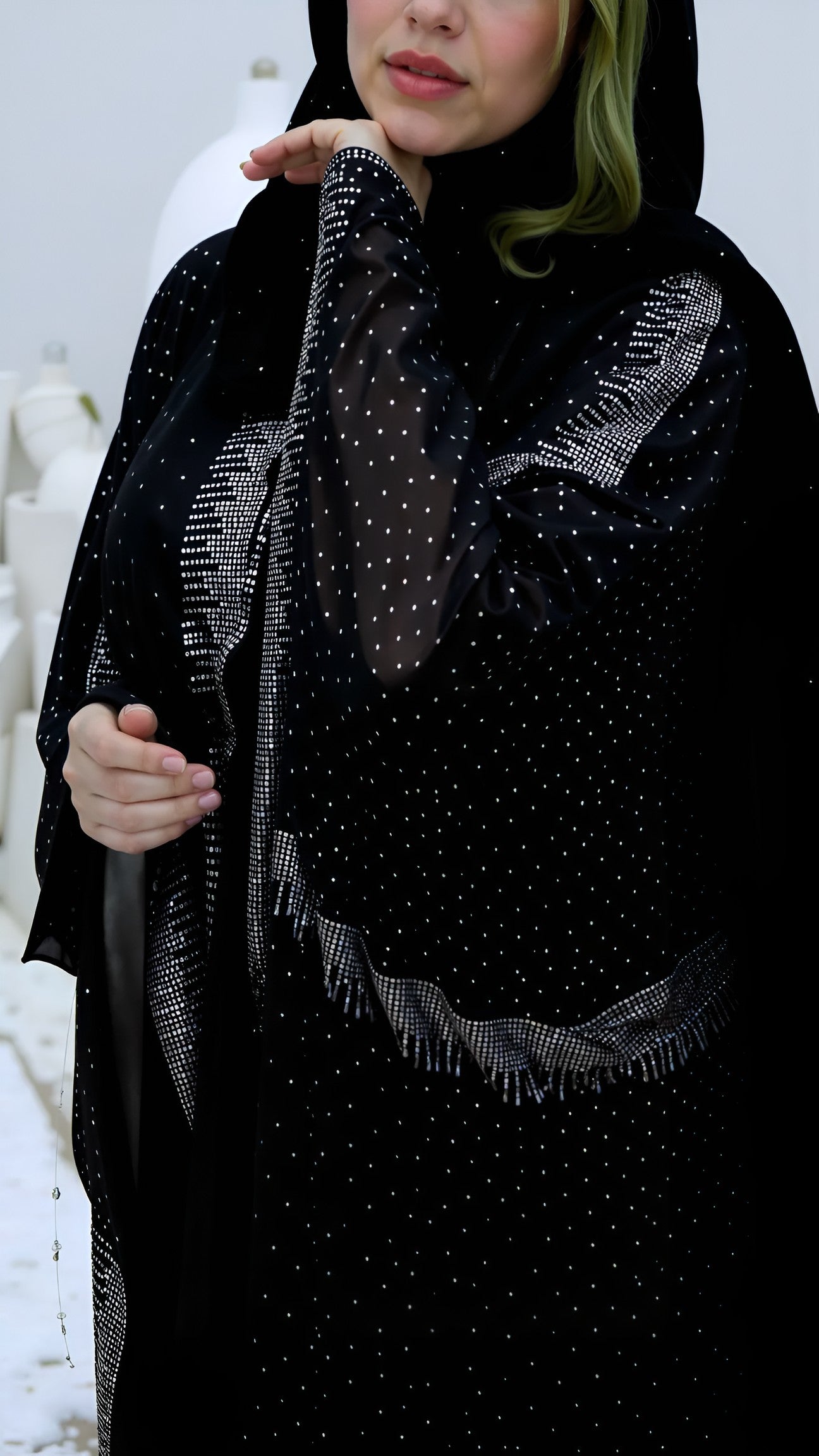 Women wearing a black abaya with intricate designs and embellishments.