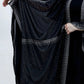 Black shawl with fringe details draped over a person on a white background