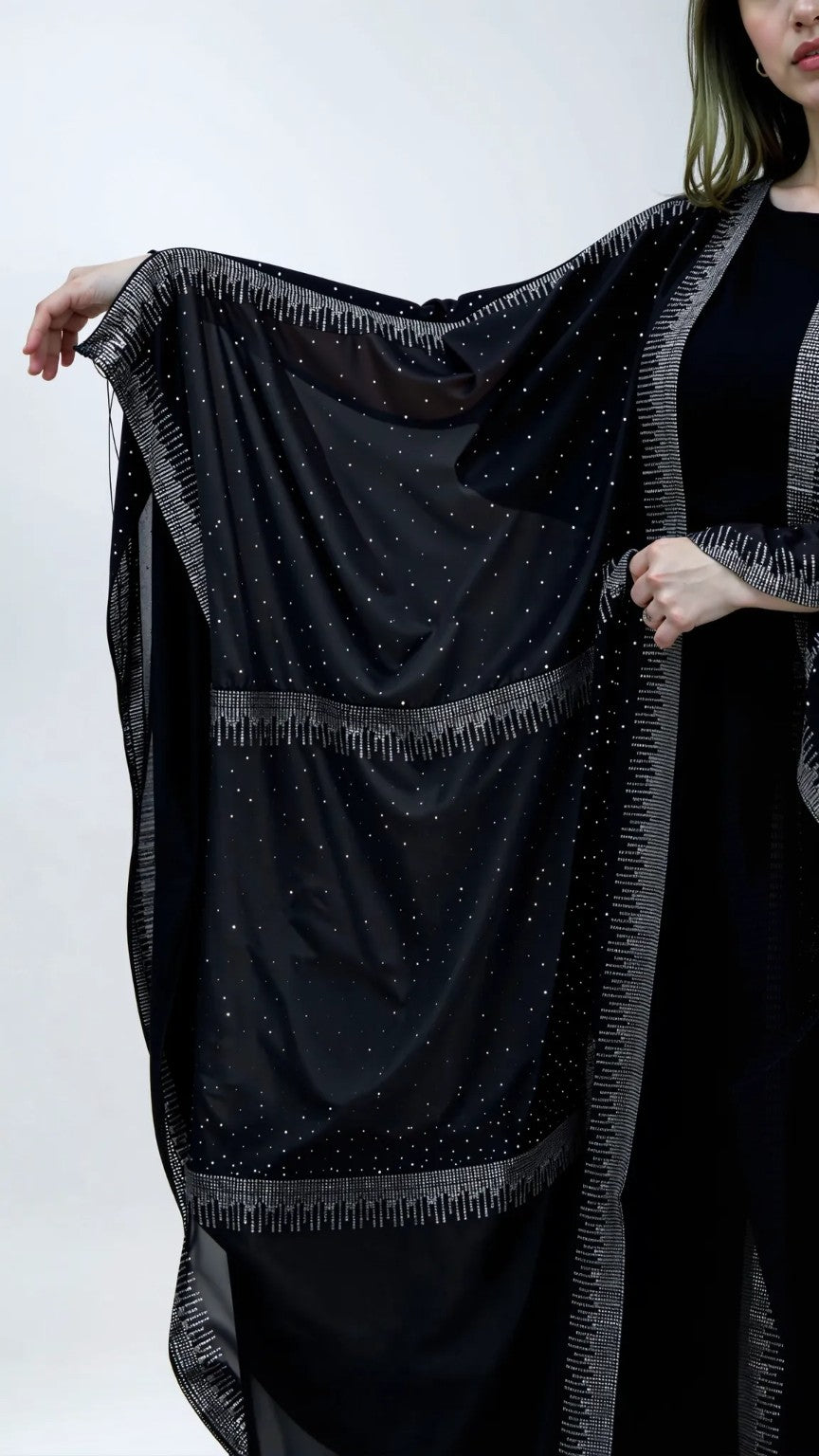 Black shawl with fringe details draped over a person on a white background