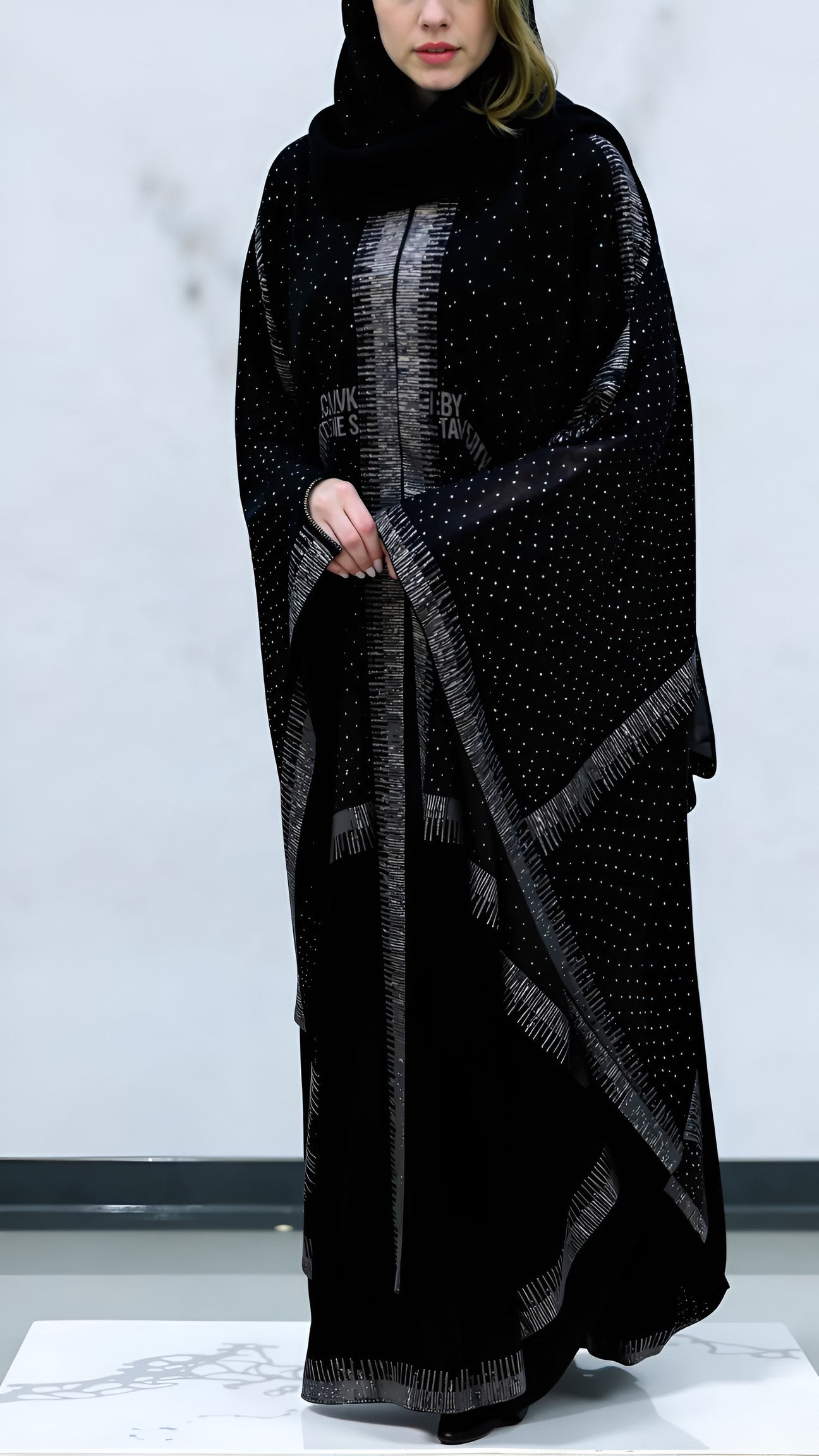 Women wearing a black patterned abaya on a white background